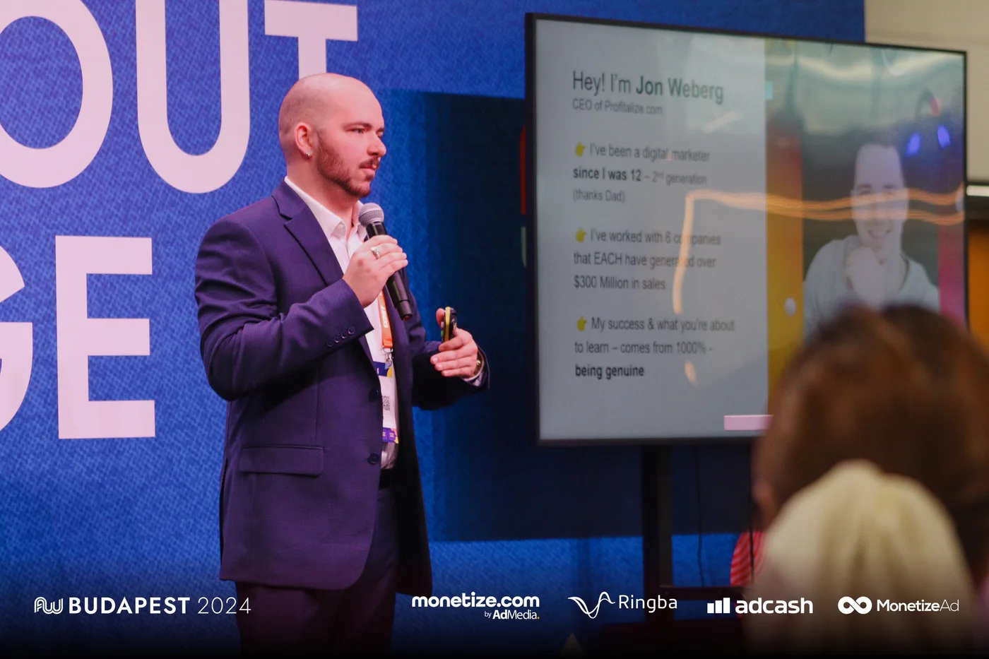 Jon Weberg keynoting at AdWorld Budapest 2024 — Profitalize.com slide on screen: I've worked with 6 companies that EACH have generated over $300 Million in sales